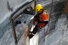 Worker using rope access in Renewable Energy industry to weld edges of inside tower