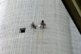 Two employees using rope access to fix side of building