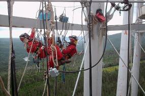Rope access technicians suspended from beams high above the ground