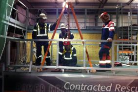 Three students observing technician being lowered in confined space for rope training