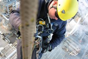 Employee in Oil & Gas industry using rope access at a pipeline refinery