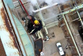 Employees using rope access to climb side of pipeline in Petrochemical industry