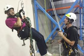 Technician in black shirt teaching student in maroon shirt rope access training