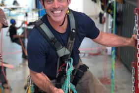 Student smiling to camera while rope training at practice facility