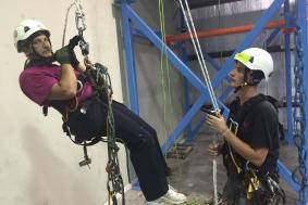 Technician in black shirt teaching student in maroon shirt rope access training