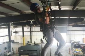 Student practicing rope access training and hanging from ceiling with ropes