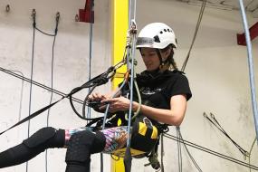 Rope access trainee suspended from ceiling in training facility