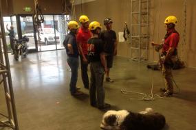 Rope access trainees inside training facility with instructor and dog