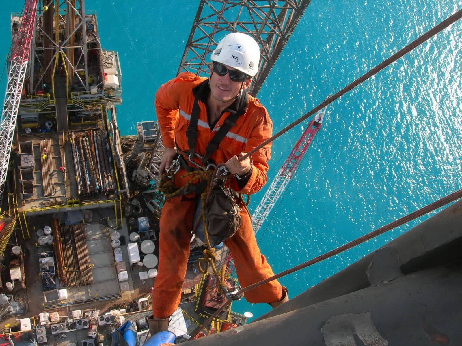 Rope access worker suspended above an ocean barge