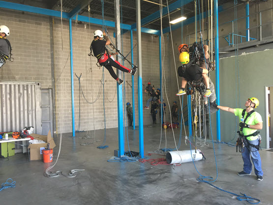 Rope access trainees with instructors training in a facility